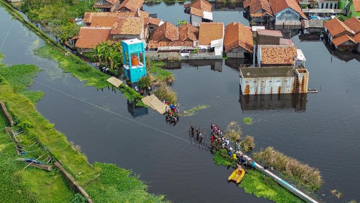 Warga berjalan melewati depan rumahnya yang tergenang banjir di Pabean, Kota Pekalongan, Jawa Tengah, Rabu (7/1/2026). Banjir setinggi sekitar 50-80 centimeter itu menggenangi perkampungan daerah Pabean yang menyebabkan aktifitas perekonomian dan pendidikan terganggu dengan sebanyak 300 KK terdampak banjir akibat tanggul Sungai Bremi jebol. ANTARA FOTO/Harviyan Perdana Putra
