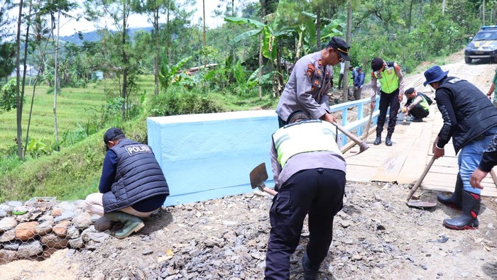 Personel Polres Pekalongan bersama warga saat bekerja bakti membangun jembatan penghubung Desa Trajumas dan Desa Bodas di Kecamatan Kandangserang, Rabu (7/1/2026).