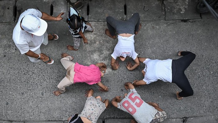 Pelatih Yoga Ardian melatih anak-anak berlatih gerakan akrobatik capoeira di gang sempit Jalan Pluit Dalam III, Penjaringan, Jakarta, Kamis (8/1/2026). Pelatih sekaligus pendiri Komunitas Indosalto, Yoga Ardian memberikan pelatihan olahraga akrobatik capoeira secara gratis sebagai kegiatan positif bagi sekitar 10-20 anak di kawasan tersebut hingga tiga diantaranya telah meraih prestasi di tingkat nasional. ANTARA FOTO/Sulthony Hasanuddin/foc.