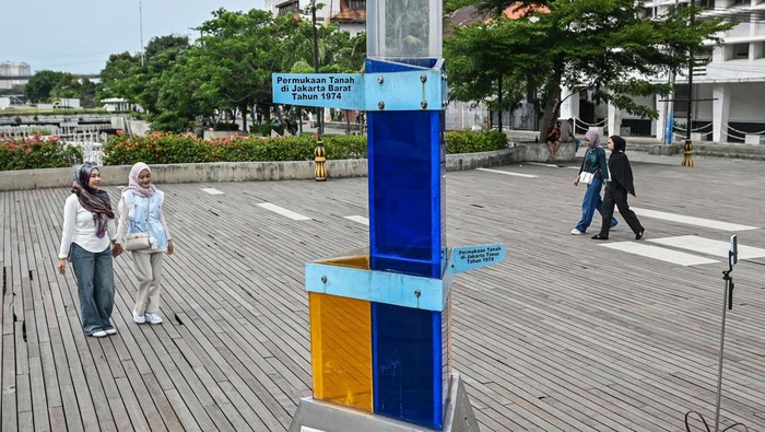 Warga berjalan di dekat Tugu Penurunan Muka Tanah di kawasan Kota Tua, Jakarta, Kamis (8/1/2026). Badan Riset dan Inovasi Nasional (BRIN) mencatat rata-rata penurunan tanah di Jakarta bagian utara terjadi sekitar 3,5 sentimeter per tahun yang berkontribusi meningkatkan risiko banjir Jakarta hingga lebih dari 40 persen sehingga perlu langkah mitigasi terutama dengan memberhentikan penggunaan air tanah. ANTARA FOTO/Sulthony Hasanuddin/foc.