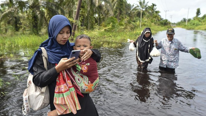 Warga menerobos jalan yang terendam banjir luapan Sungai Dendang di Desa Catur Rahayu, Tanjung Jabung Timur, Jambi, Sabtu (10/1/2026). Akses kendaraan di beberapa titik di desa itu terputus sejak Jumat (9/1) akibat ketinggian air hampir mencapai 1 meter, sementara data BPBD setempat menyebutkan sebanyak 149 kepala keluarga dilaporkan terdampak. ANTARA FOTO/Wahdi Septiawan/rwa.