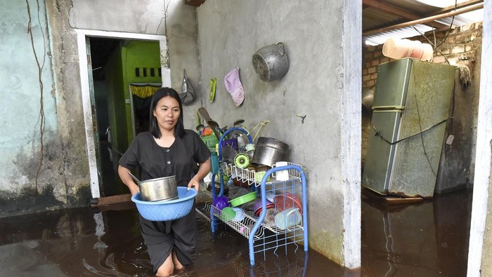 Warga memindahkan peralatan dapur di dalam rumahnya yang terendam banjir luapan Sungai Dendang di Desa Catur Rahayu, Tanjung Jabung Timur, Jambi, Sabtu (10/1/2026). Akses kendaraan di beberapa titik di desa itu terputus sejak Jumat (9/1) akibat ketinggian air hampir mencapai 1 meter, sementara data BPBD setempat menyebutkan sebanyak 149 kepala keluarga dilaporkan terdampak. ANTARA FOTO/Wahdi Septiawan/rwa.