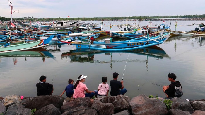 Sejumlah warga memancing di area Dermaga Pelabuhan Tempat Pelelangan Ikan (TPI) Pantai Gerajagan, Banyuwangi, Jawa Timur, Minggu (11/1/2026). Badan Meteorologi, Klimatologi, dan Geofisika (BMKG) memperkirakan tinggi gelombang di Perairan selatan Jawa mencapai 2,5 hingga 4 meter disertai angin kencang dan hujan sehingga membuat sebagian besar nelayan setempat tidak melaut untuk menghindari resiko keselamatan berlayar. ANTARA FOTO/ Budi Candra Setya