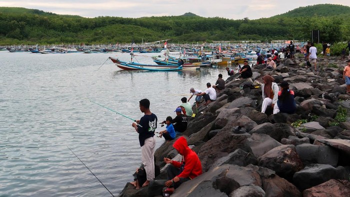 Sejumlah warga memancing di area Dermaga Pelabuhan Tempat Pelelangan Ikan (TPI) Pantai Gerajagan, Banyuwangi, Jawa Timur, Minggu (11/1/2026). Badan Meteorologi, Klimatologi, dan Geofisika (BMKG) memperkirakan tinggi gelombang di Perairan selatan Jawa mencapai 2,5 hingga 4 meter disertai angin kencang dan hujan sehingga membuat sebagian besar nelayan setempat tidak melaut untuk menghindari resiko keselamatan berlayar. ANTARA FOTO/ Budi Candra Setya