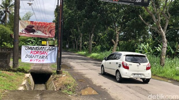 Spanduk-spanduk protes dan pohon pisang yang ditanam warga Tangisan Sleman di ruas jalan Tempel-Dekso, Minggu (11/1/2026).