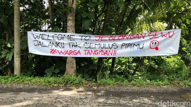 Spanduk-spanduk protes dan pohon pisang yang ditanam warga Tangisan Sleman di ruas jalan Tempel-Dekso, Minggu (11/1/2026).