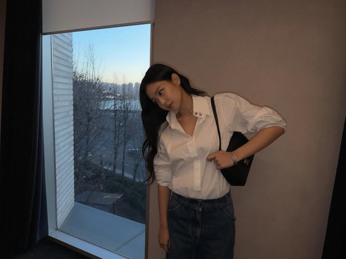 Jennie BLACKPINK bergaya simpel dengan celana jins dan kemeja putih.