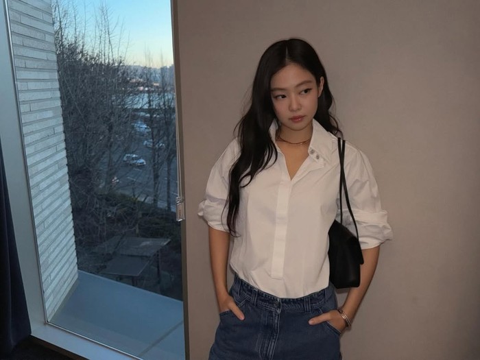 Jennie BLACKPINK bergaya simpel dengan celana jins dan kemeja putih.