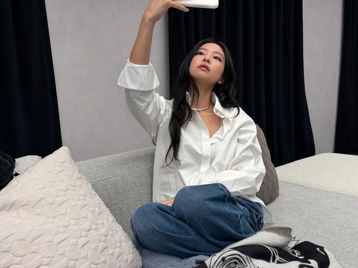 Jennie BLACKPINK bergaya simpel dengan celana jins dan kemeja putih.