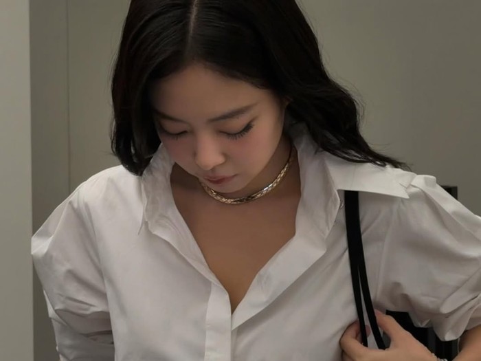 Jennie BLACKPINK bergaya simpel dengan celana jins dan kemeja putih.