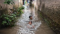 Anak-anak tampak bermain di tengah banjir, sementara sebagian warga tetap beraktivitas meski harus beradaptasi dengan kondisi lingkungan yang tergenang. ANTARA FOTO/Sulthony Hasanuddin  