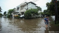 Warga yang melintas terlihat ekstra hati-hati saat beraktivitas di jalan yang berubah menjadi kubangan air.