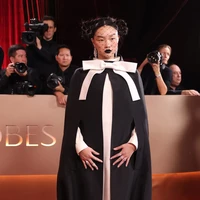 Masih dari trio KPop Demon Hunters, Audrey Nuna mencuri perhatian dengan gaya eksperimental. Ia mengenakan jubah hitam menyerupai kado berhias pita pink besar di bagian leher dan pergelangan kaki. Pengisi suara Mira itu bahkan menutupi wajahnya dengan veil berjaring, dan memakai lipstik hitam. Foto: Getty Images