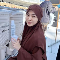 Ayana tampil tanpa makeup dengan hijab instan berwarna cokelat tua yang memiliki potongan praktis dan menutupi dada. Gaya ini memberikan kesan nyaman dan tetap rapi saat ia sedang beristirahat sambil menikmati air zam-zam di area Masjidil Haram. Foto: Dok. Instagram @xolovelyayana.