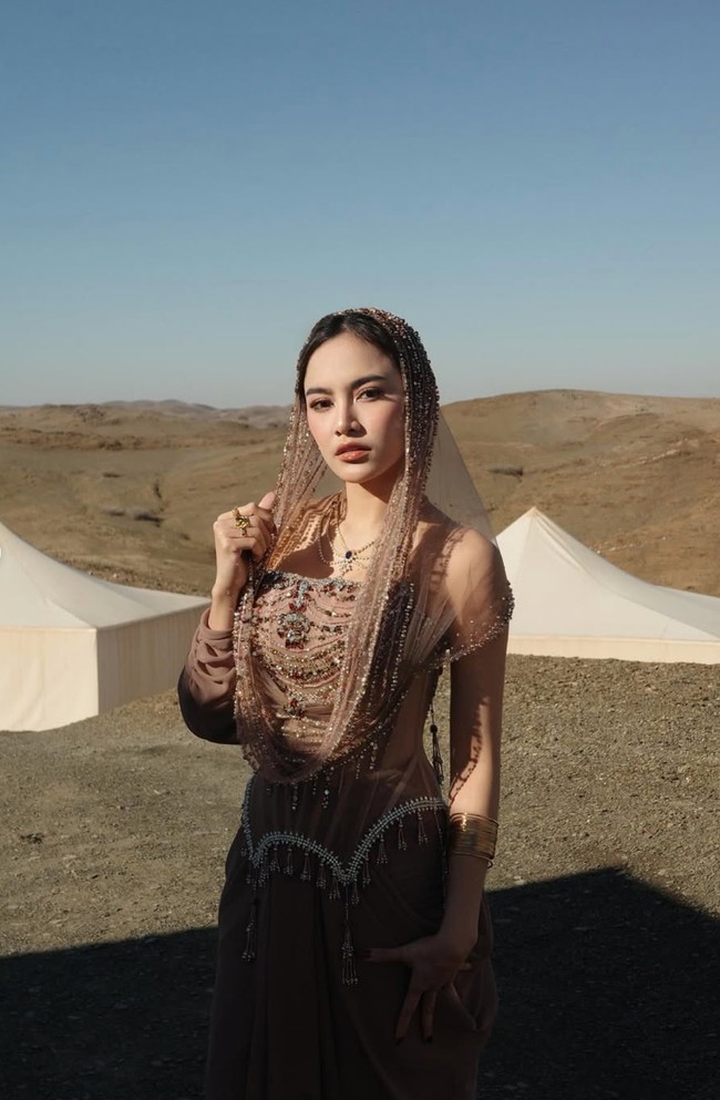 Mahalini tampil kian memukau dengan tudung atau hood transparan bernuansa keemasan. Hooded tersebut dihiasi rangkaian manik-manik dan detail berkilau yang menjuntai lembut mengikuti garis wajah hingga bahu. Foto: Instagram/@mahaliniraharja