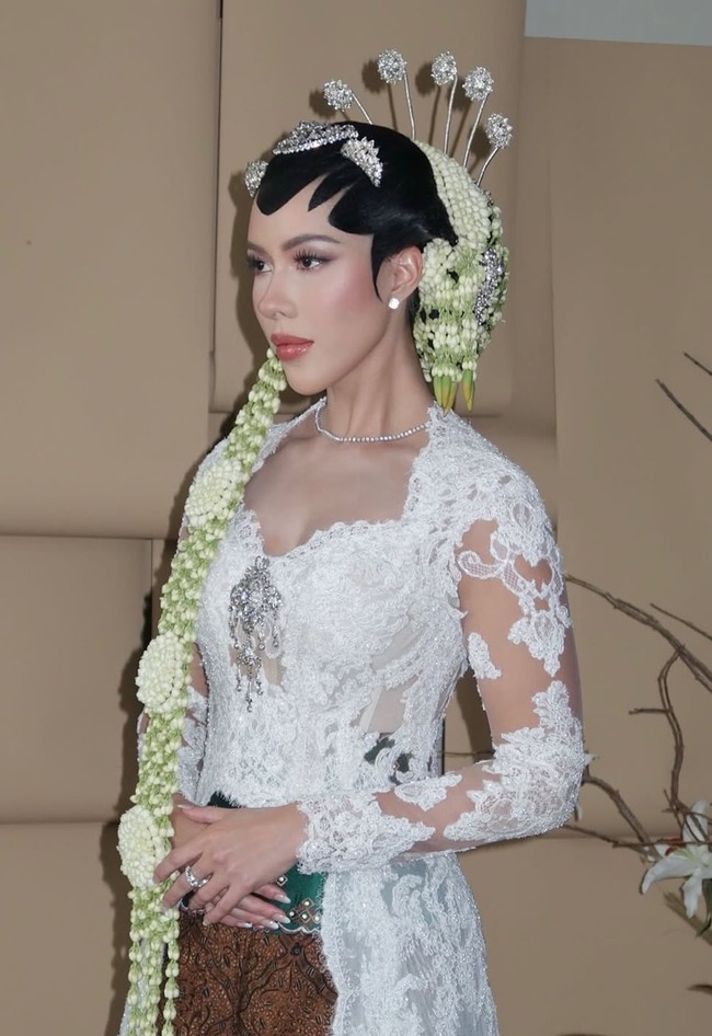 Kebaya dipadukan dengan kain batik cokelat bermotif klasik yang elegan. Kontras warna putih dan cokelat menciptakan harmoni adat Jawa yang kuat, diperindah dengan stagen hijau zamrud bermotif emas sebagai aksen pinggang. Foto: Instagram/@rhay_david