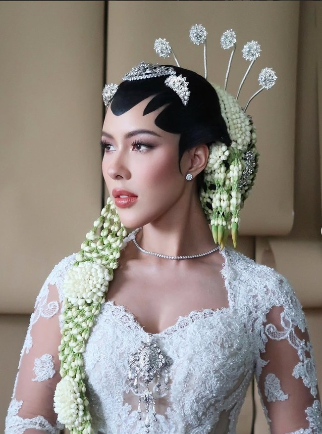 Rambut Patricia ditata dalam sanggul tradisional dengan paes hitam yang tegas di dahi. Sanggul dihiasi rangkaian melati panjang yang menjuntai anggun hingga depan, dipadukan dengan cunduk mentul beraksen perak berkilau. Foto: Instagram/@rhay_david