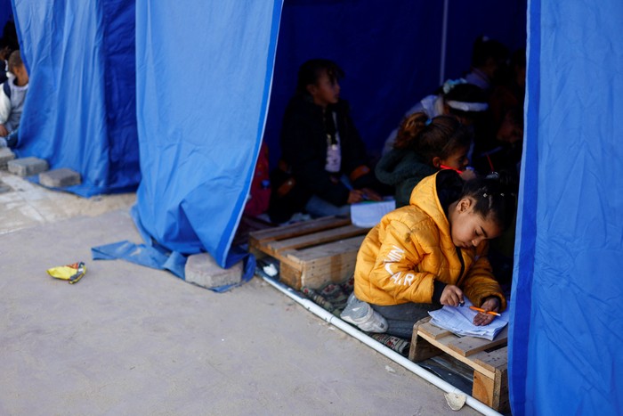 Displaced Palestinian students study inside a tent near the Israeli-designated 