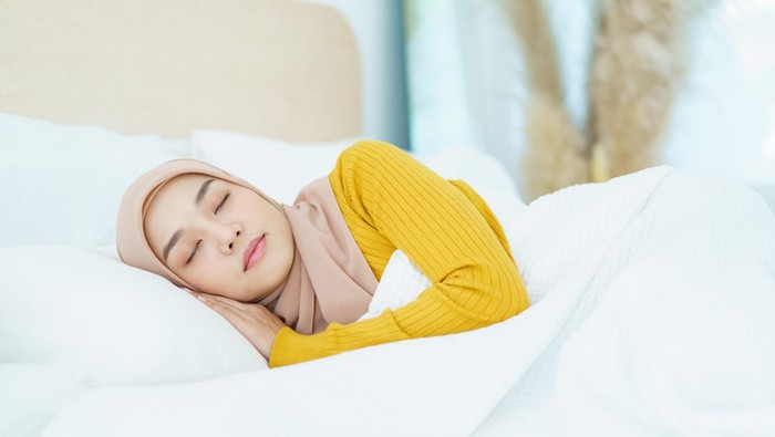 Beautiful Asian muslim young woman sleeping - relaxing on the bed during the day. Cozy and relaxing lifestyle of modern muslim woman concept.