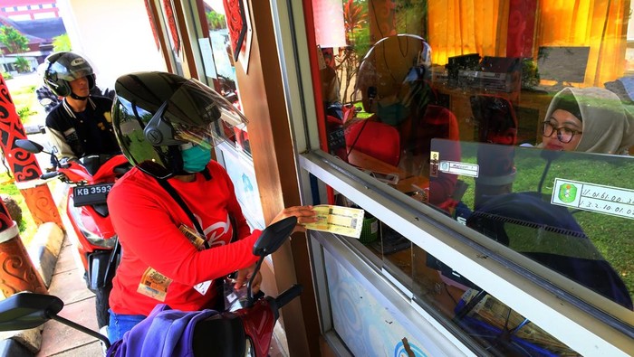 Sejumlah pengendara motor antre membayar Pajak Kendaraan Bermotor (PKB) melalui layanan tanpa turun (Lantatur) di halaman Museum Kalbar, Pontianak, Kalimantan Barat, Rabu (14/1/2026). Samsat Lantatur yang beroperasi tujuh hari dalam seminggu tersebut untuk memudahkan masyarakat membayar pajak kendaraan bermotor roda dua dan roda empat secara cepat dan praktis tanpa harus turun dari kendaraan, sehingga meningkatkan efisiensi serta kenyamanan pelayanan publik. ANTARA FOTO/Jessica Wuysang/rwa.
