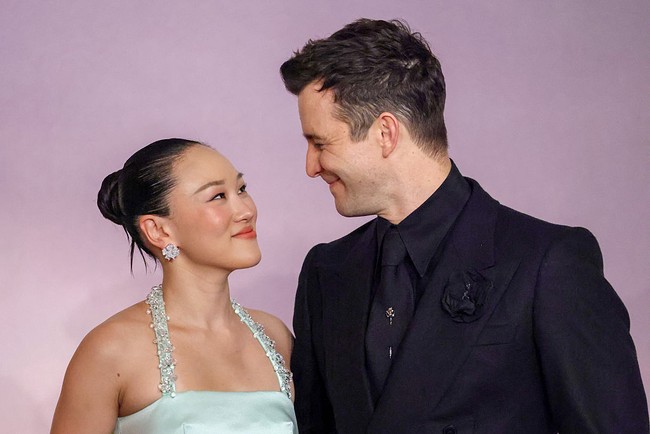 Yerin Ha berpose bersama ‘pacarnya’ di Bridgerton, Luke Thompson yang tampil monokrom dalam setelan hitam dengan detail floral di kerah dan peniti dasi perak. Foto: Getty Images/Stephane Cardinale