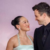 Yerin Ha berpose bersama ‘pacarnya’ di Bridgerton, Luke Thompson yang tampil monokrom dalam setelan hitam dengan detail floral di kerah dan peniti dasi perak. Foto: Getty Images/Stephane Cardinale