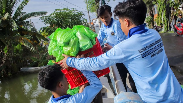 Petugas Satuan Pelayanan Pemenuhan Gizi (SPPG) Dapur Carnis mendistribusikan bingkisan Makanan Bergizi Gratis (MBG) menggunakan perahu di Deket, Lamongan, Jawa Timur, Kamis (15/1/2026). Petugas SPPG setempat menyalurkan sebanyak 600 bingkisan MBG untuk 35 sekolah dan ibu hamil menggunakan perahu di tujuh desa yang terdampak banjir luapan Sungai Bengawan Jero. ANTARA FOTO/Rizal Hanafi