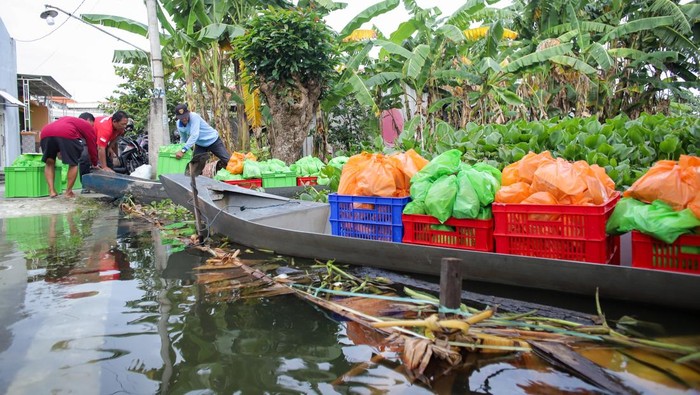 Petugas Satuan Pelayanan Pemenuhan Gizi (SPPG) Dapur Carnis mendistribusikan bingkisan Makanan Bergizi Gratis (MBG) menggunakan perahu di Deket, Lamongan, Jawa Timur, Kamis (15/1/2026). Petugas SPPG setempat menyalurkan sebanyak 600 bingkisan MBG untuk 35 sekolah dan ibu hamil menggunakan perahu di tujuh desa yang terdampak banjir luapan Sungai Bengawan Jero. ANTARA FOTO/Rizal Hanafi