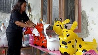 Aneka pot bunga dengan karakter sapi, gajah hingga jerapah berjajar di teras rumah Mimi Hani.