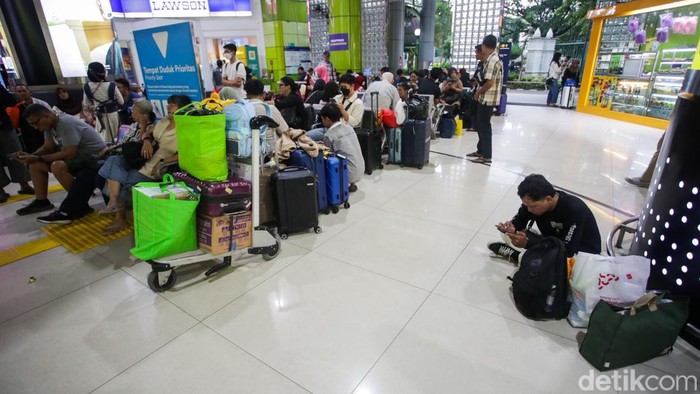 Sejumlah penumpang menunggu kedatangan kereta yang mengalami keterlambatan di Stasiun Gambir, Jakarta, Minggu (18/1/2026), akibat cuaca ekstrem.