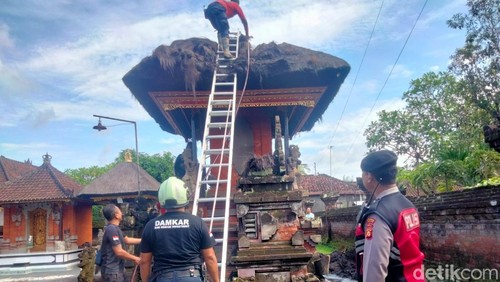 Petugas Damkar Badung memadamkan sisa api di atap palinggih gedong di sebuah pura di Sibangkaja, Abiansemal, Badung, Minggu siang. (Agus Eka/detikBali)
