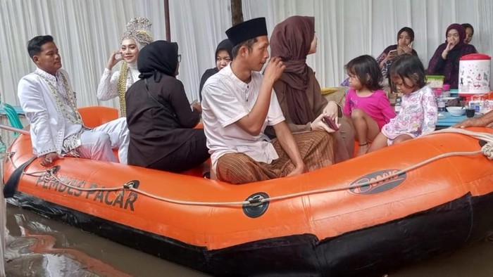 Pengantin naik perahu karet di Desa Sepacar, Kecamatan Tirto, Kabupaten Pekalongan, Minggu (18/1/2026).