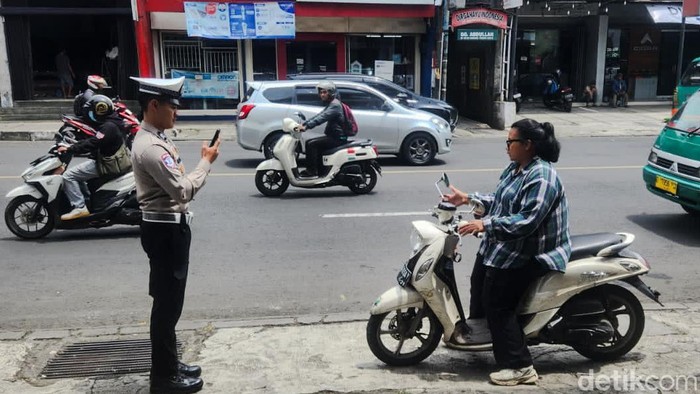 polisi tilang pelanggar lalu lintas dengan ETLE Mobile Handheld
