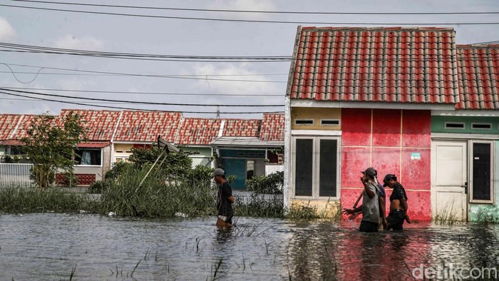 Warga beraktivitas di kawasan perumahan subsidi Green Lavender Sukamekar, Kabupaten Bekasi, Jawa Barat, Senin (19/1/2026), yang kembali terendam banjir.
