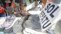 Pekerja menyelesaikan perbaikan sol sepatu, salah satu layanan yang juga banyak diminati pelanggan di lapak tersebut.