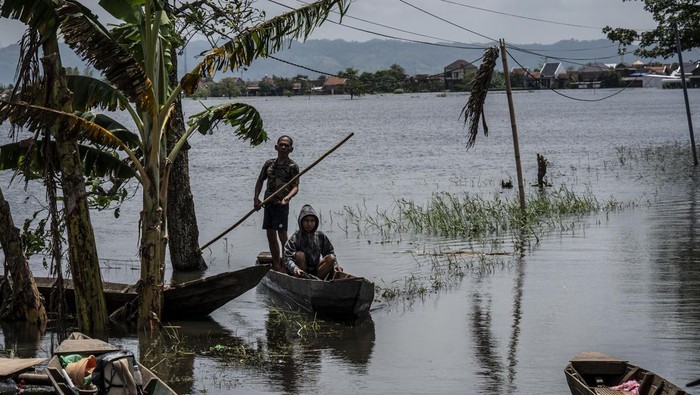 Warga menggunakan rakit untuk menyeberangi akses jalan yang terendam banjir di Desa Mejobo, Kudus, Jawa Tengah, Senin (19/1/2026). Warga setempat terpaksa menggunakan rakit dan perahu bermesin untuk menunjang mobilitas sehari-hari di tengah banjir hidrometeorologi yang merendam permukiman dan melumpuhkan akses transportasi darat. ANTARA FOTO/Aprillio Akbar/wsj.