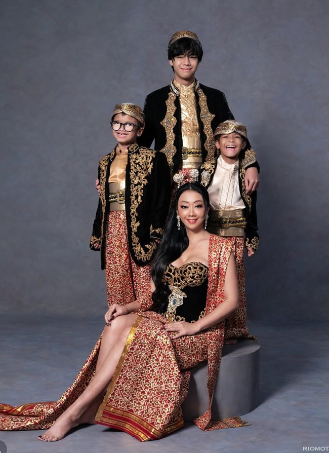 Sementara look kedua tampak bernuansa tradisional dengan balutan busana adat. Asri dan ketiga putranya tampil kompak dalam warna dominan merah, emas, dan hitam. Foto: Instagram/@riomotret