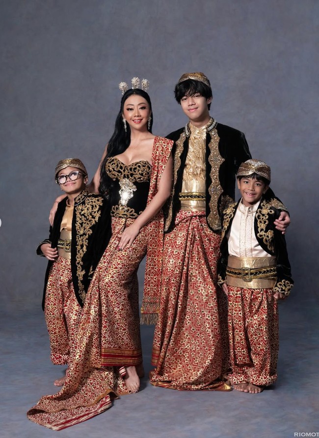 Asri mengenakan bustier hitam dengan bordir emas yang mewah, dipadukan kain songket merah bermotif emas. Selendang merah senada beraksen emas disampirkan di bahu, menambah kesan anggun. Foto: Instagram/@riomotret