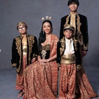 Busana yang dikenakan Asri di kedua look tersebut tampak memiliki potongan dada cukup rendah, memberikan kesan seksi dalam keseluruhan tampilan. Sementara ketiga putranya tampil serasi dalam setelan adat berupa atasan hitam berbordir emas, kain songket merah, serta ikat pinggang emas. Foto: Instagram/@riomotret