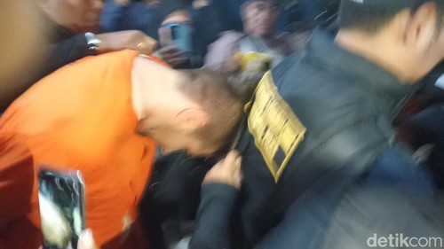 Buronan Interpol Costinel-Cosmin Zuleam menunduk saat digiring ke mobil tahanan di Polda Bali, Selasa (20/1/2026).