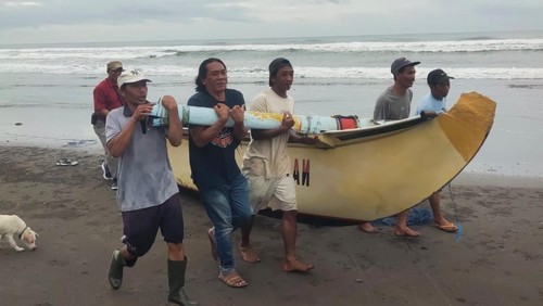 Masyarakat saat melakukan evakuasi perahu nelayan yang terdampar dalam kondisi terbalik di Pantai Banjar Anyar Tembles, Desa Penyaringan, Kecamatan Mendoyo, Kabupaten Jembrana, Bali, Selasa (20/1/2026). (Polres Jembrana)