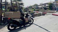 Kasi mulai menjaga perlintasan itu sejak 1991. Ia berjaga di sana menghentikan arus kendaraan agar tak terjadi kecelakaan dengan kereta. Palangnya masih manual. Tak ada pos resmi, tak ada sistem otomatis.