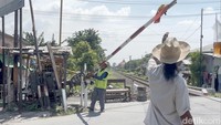Tangannya sigap menarik palang manual, sementara matanya awas menembus kejauhan, mengantisipasi laju kereta yang datang.
