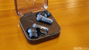 Nothing Ear (3) tetap mempertahankan DNA desain transparan khas Nothing, namun kini mengadopsi struktur metalik terintegrasi yang memberikan kesan lebih premium. Komponen logam yang dipoles menyatu dengan bodi transparan, menonjolkan estetika futuristik. Foto: Adi Fida Rahman/detikINET