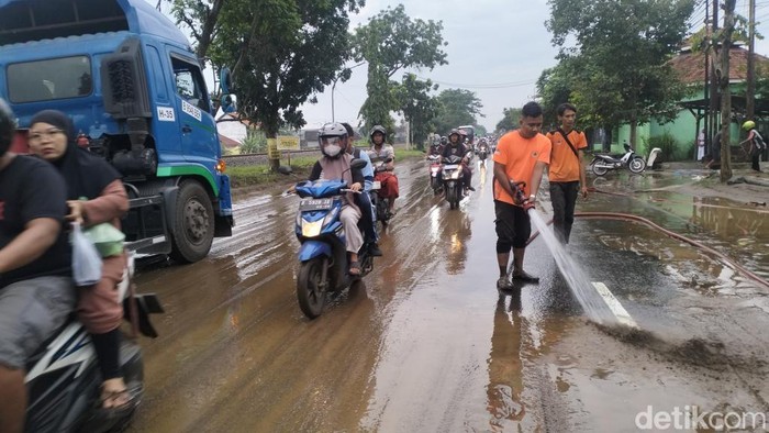Petugas membersihkan lumpur sisa banjir di Pantura Pasuruan