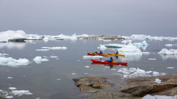 Sekelompok orang kayak di antara gunung es di Ilulissat Icefjord. Ilulissat Icefjord dinyatakan sebagai Situs Warisan Dunia UNESCO pada tahun 2004.