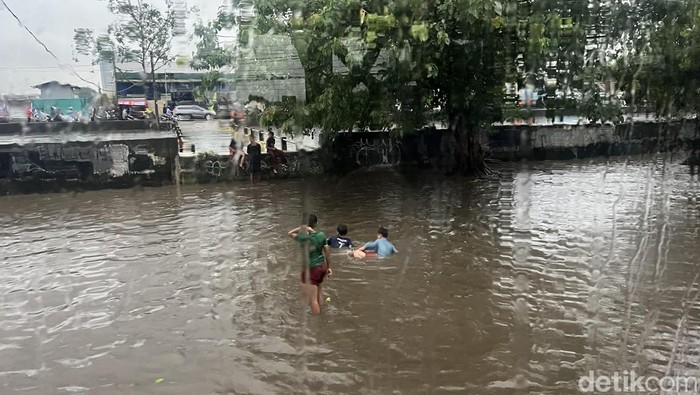 Anak-anak Berenang Saat Banjir di Jalan Daan Mogot