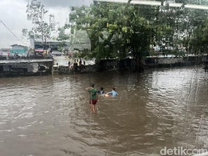 Anak-anak Berenang Saat Banjir di Jalan Daan Mogot