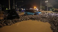 Jalanan dipenuhi air dan puing-puing, sementara sejumlah kendaraan rusak tertimpa material yang terbawa badai. REUTERS/Louisa Gouliamaki  