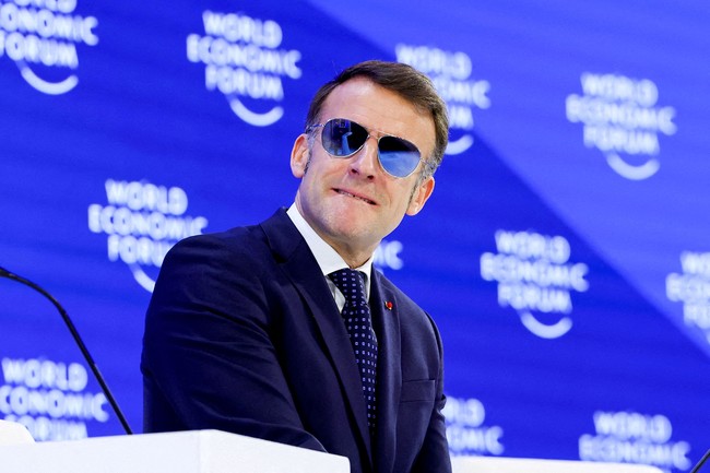 Di WEF yang berlangsung di Davos, Swiss, pada  Rabu (21/1/2026), Macron berpakaian rapi dalam balutan setelan, lengkap dengan dasi. Namun kontras dari gaya formalnya, sebuah kacamata aviator berlensa cermin yang menutupi matanya. (Foto: REUTERS/Denis Balibouse)